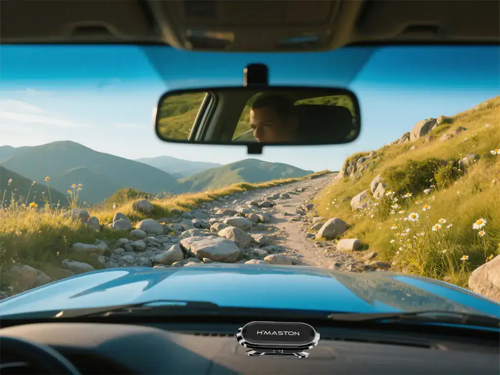Caminho de terra em meio à natureza, com o visual de montanhas ao fundo, visto do interior de um carro H'Maston durante a aventura off-road.
