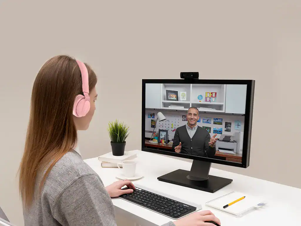 Profissional de atendimento online conversando em vídeo chamada com cliente ou colega de trabalho, usando computador no escritório.