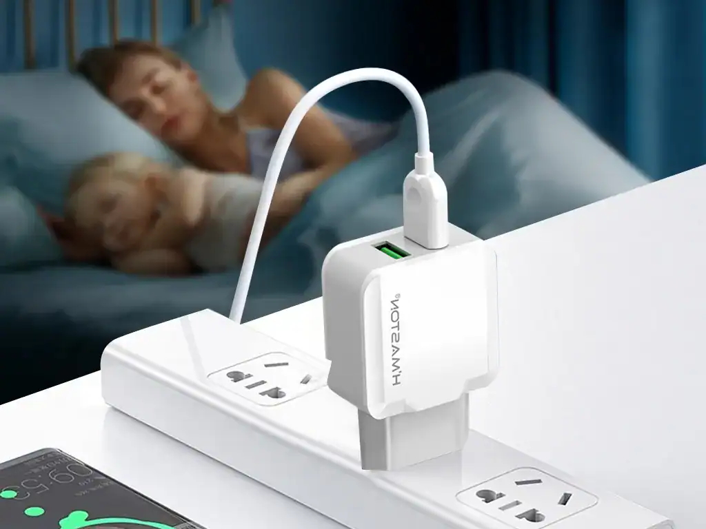 Carregador USB com adaptador para tomadas brasileiras, conectado a uma extensão elétrica, carregando um smartphone. Família descansando na cama ao fundo, ambiente residencial confortável e moderno.