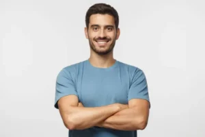 homem bonito sorrindo no pé de t shirt azul com braços cruzados isolad