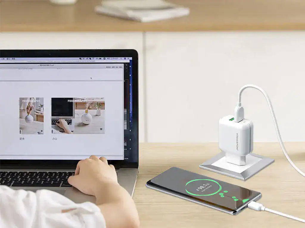 Carregador portátil H'MASTON em uso com smartphone e laptop, promovendo carregamento eficiente e estilo moderno.