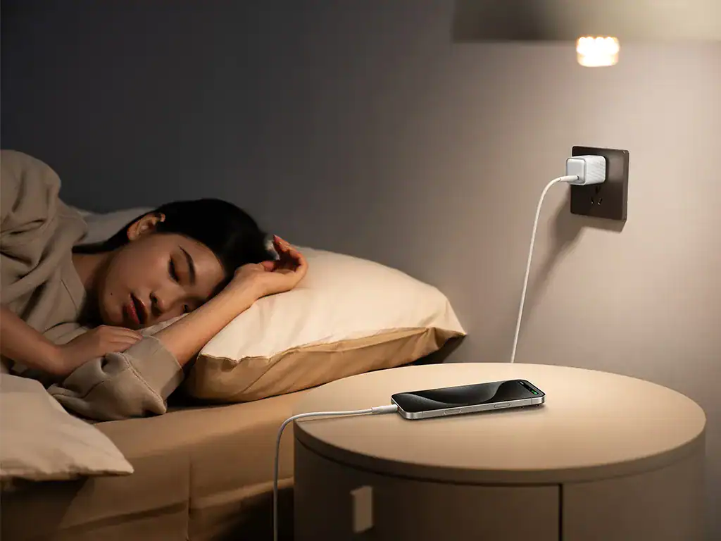 Carregador portátil para celular na tomada, mulher deitada descansando, ambiente de noite, tecnologia, conveniência, carregamento rápido.