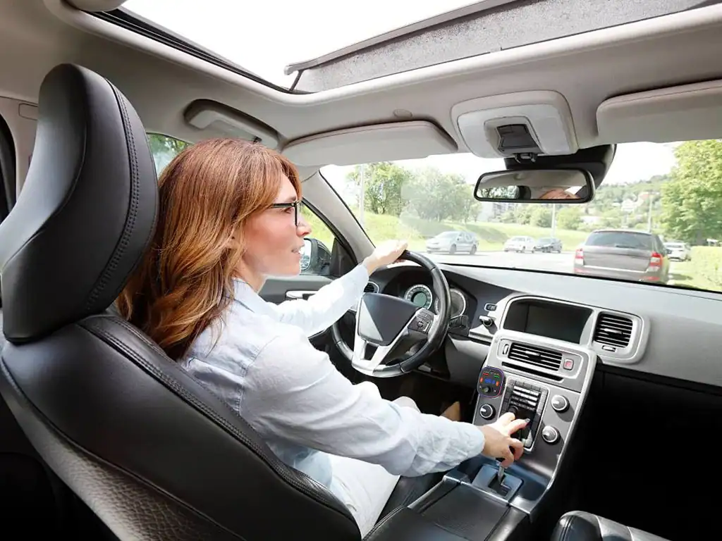 Mulher dirigindo carro com atenção ao volante, interior moderno e confortável, ideal para viagens e deslocamentos diários.